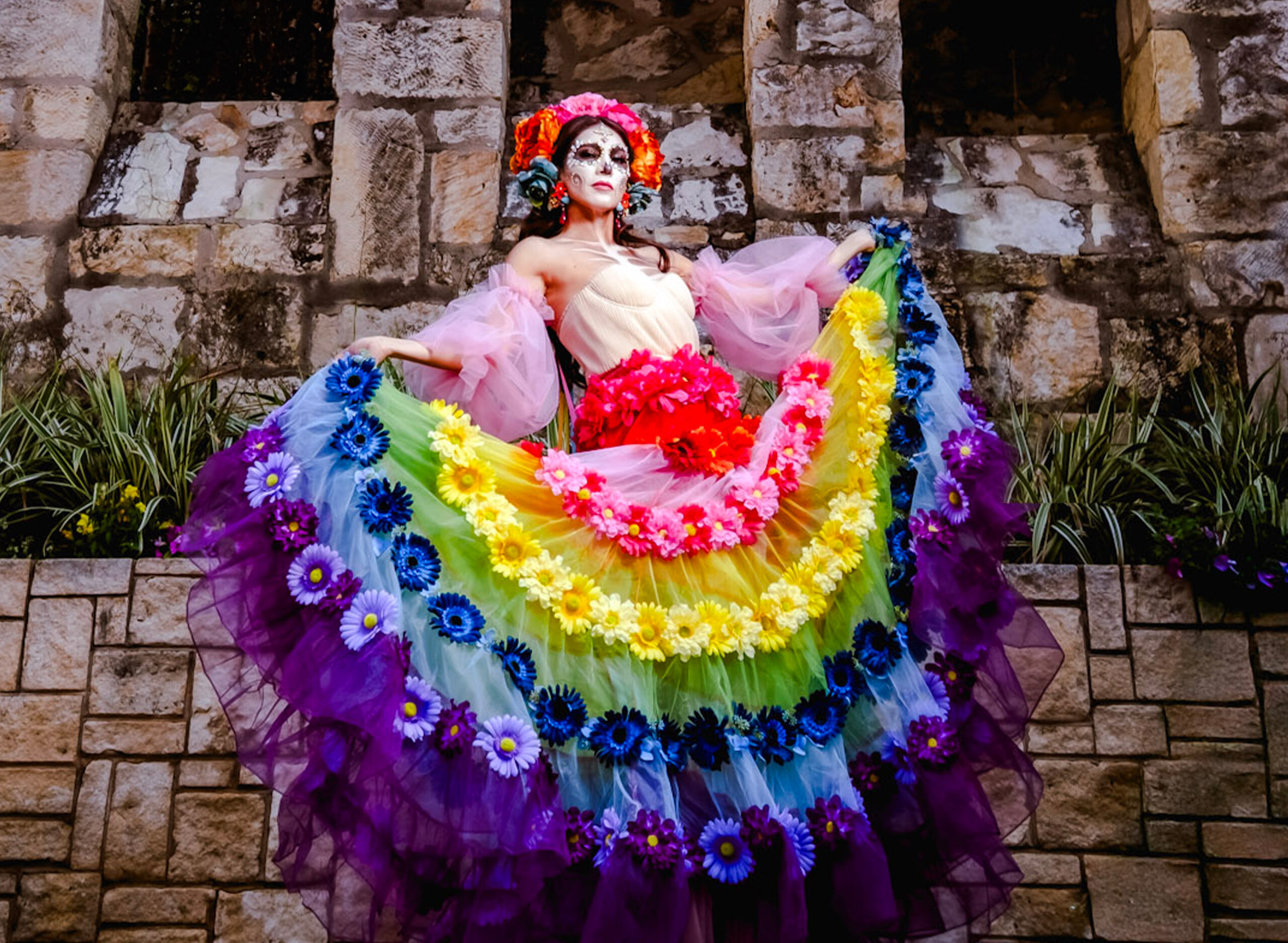 Fiesta Catrina captures the essence of that tradition. Her full circle skirt evokes the graceful movements of folkloric dance, symbolizing the rhythm and resilience of Mexican culture. Crafted from layers of colorful organza, the ensemble mirrors the vibrant wreaths that adorn San Antonio’s doors during Fiesta season—radiating joy, pride, and cultural unity.