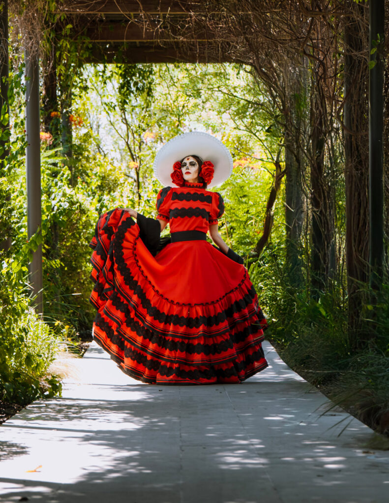 Catrina Escaramuza celebrates the elegance and discipline of charrería, Mexico’s national sport and a treasured cultural art. Wearing an authentic gown crafted in Mexico by Camelia Mexican Boutique in collaboration with iLaCatrina, she honors the tradition of the escaramuza charra with grace, pride, and timeless beauty.